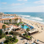 Hotel Club La Serena resort with pool, palm trees, beach umbrellas, and ocean view